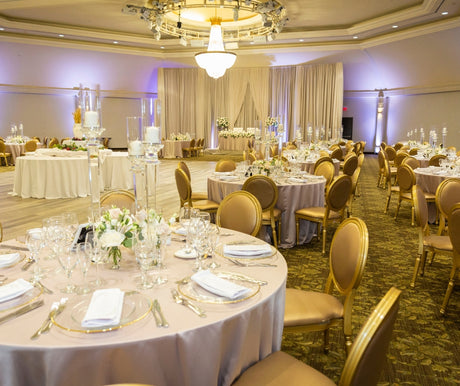 Decorated banquet hall with round tables, chairs, and floral centerpieces.